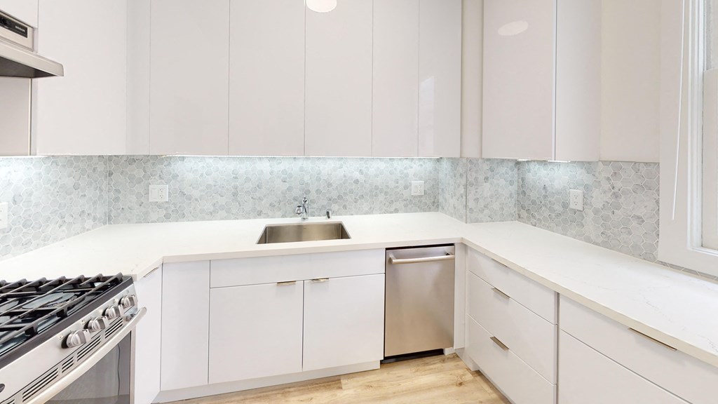 a white kitchen with white cabinets and stainless steel appliances