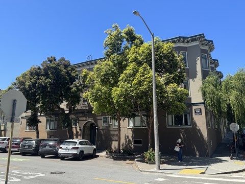 A street view with a building, cars, and a pedestrian.