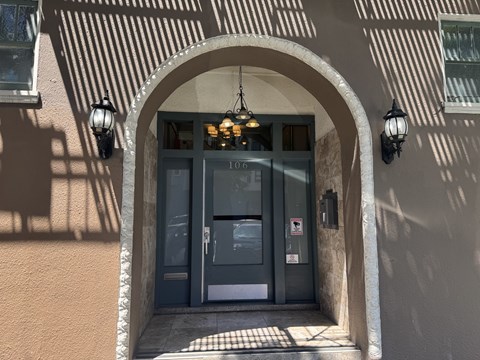 The image shows a building entrance with a glass door and a sign that reads "106".