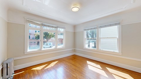 A sunny room with wooden floors and windows.