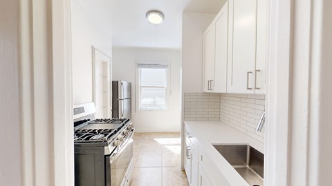 A kitchen with white cabinets and a black stove top oven.