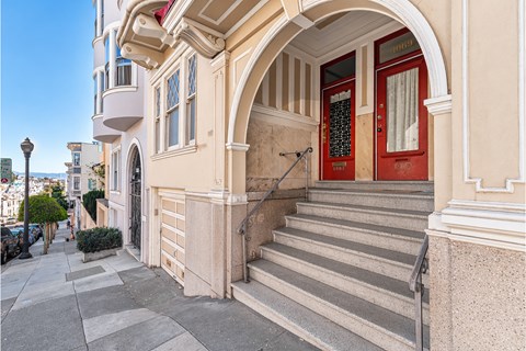 A building with a red door and a staircase leading to it.