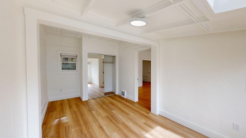A long hallway with wood floors and white walls.