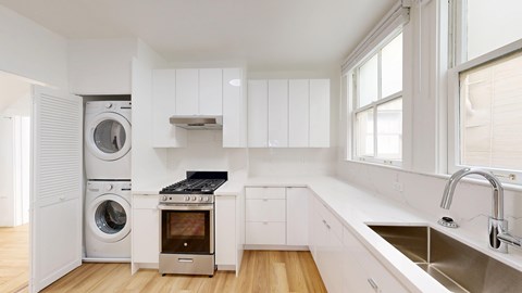 A modern kitchen with a washing machine and dryer built into the cabinetry.