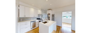 a white kitchen with a large island and stainless steel appliances