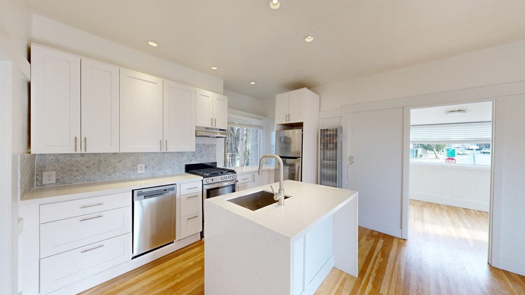 a white kitchen with a large island and stainless steel appliances