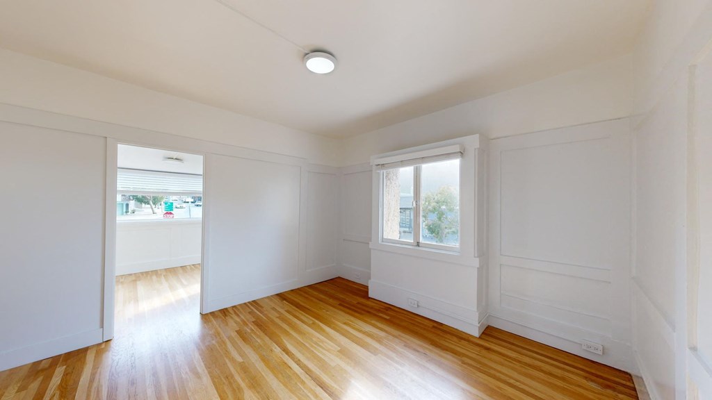 an empty living room with white walls and wood floors