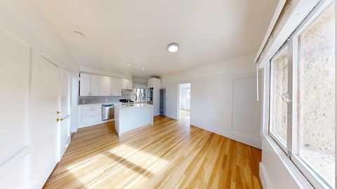A kitchen with white cabinets and a wooden floor.