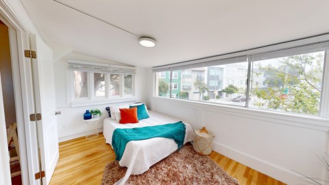 A bedroom with a bed, pillows, and a rug.