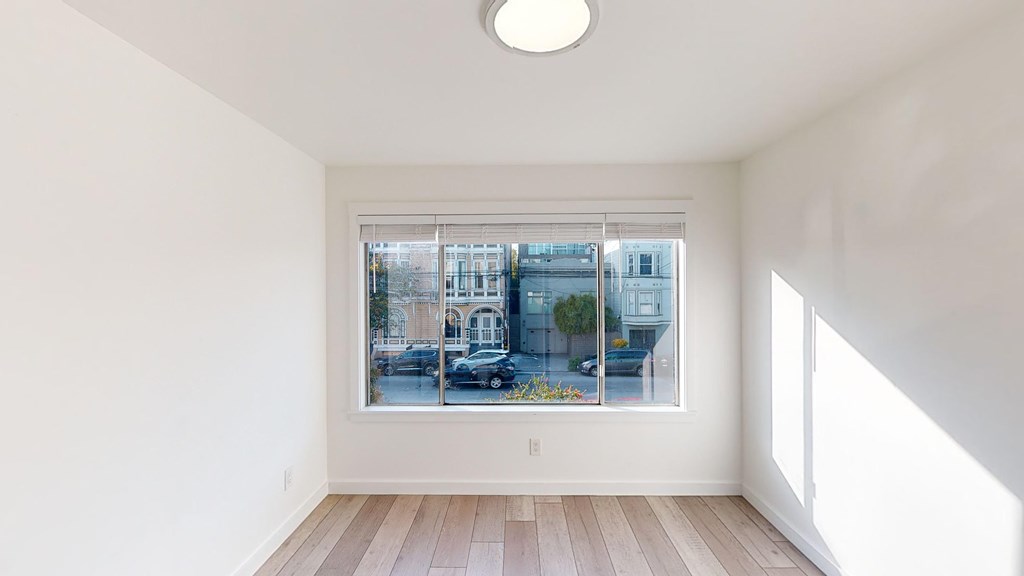 A room with a large window showing a street view outside.