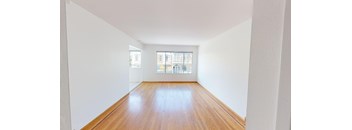 an empty room with wood floors and a window