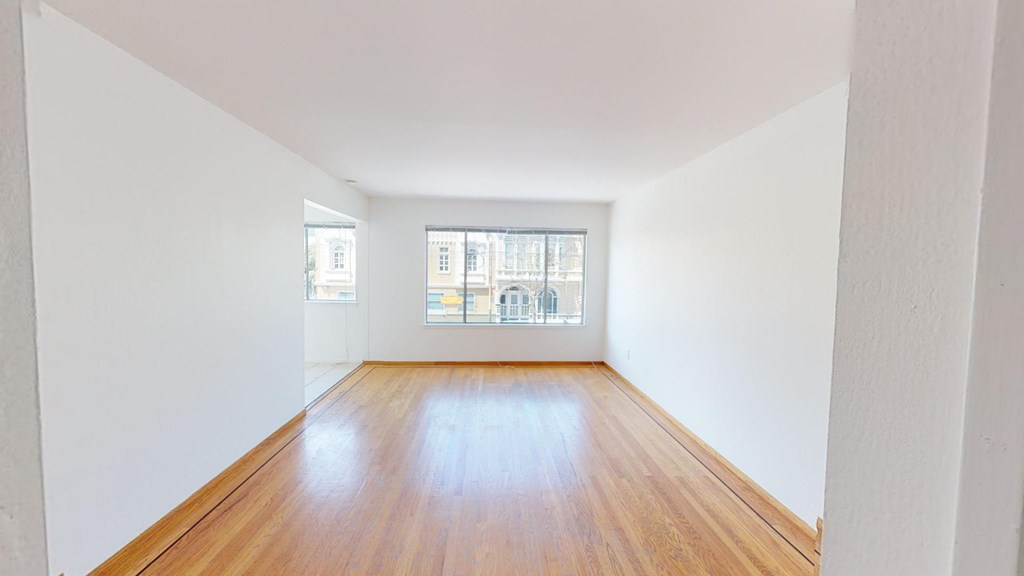 an empty room with wood floors and a window