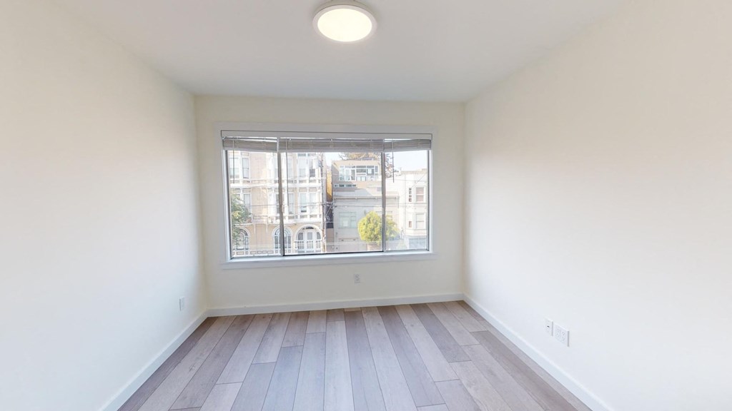 a living room with a large window and wooden floors