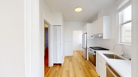 A kitchen with white cabinets and a wooden floor.