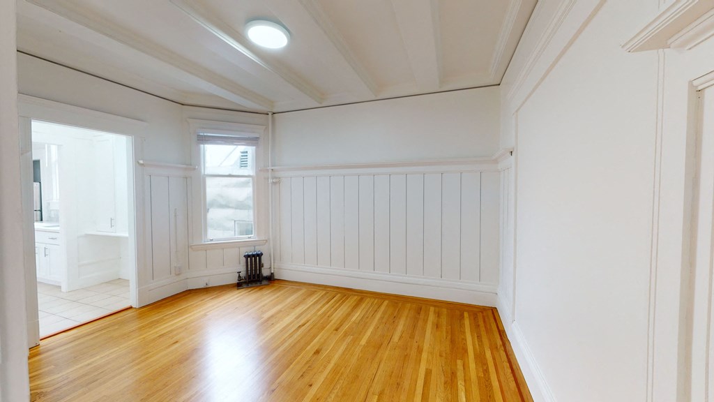 an empty living room with white walls and wood floors