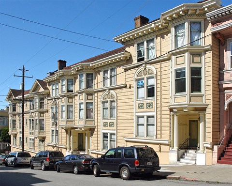 a row of houses on a street with cars parked in front