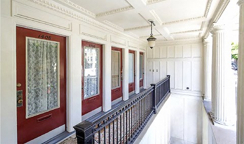 a long hallway with red doors and white walls and a black railing