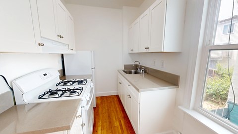 A small kitchen with a white stove and cabinets.