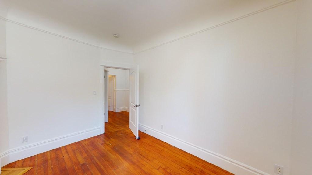 a bedroom with white walls and wood floors