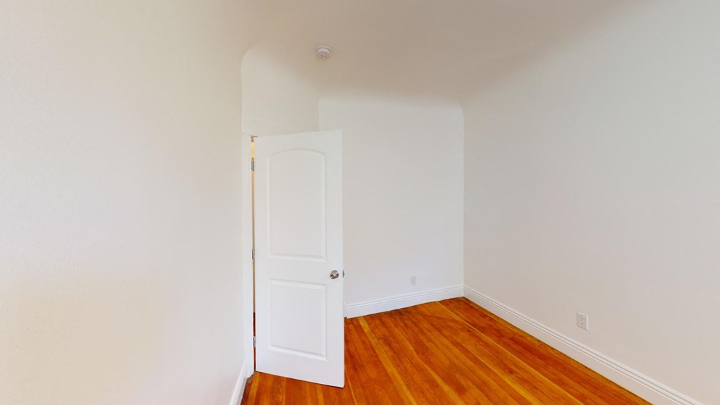 a bedroom with a wooden floor and a white door