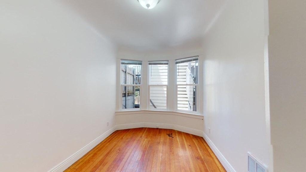 a bedroom with three windows and a wood floor