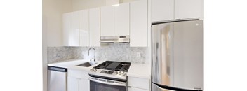 a white kitchen with stainless steel appliances and white cabinets