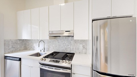 a white kitchen with stainless steel appliances and white cabinets