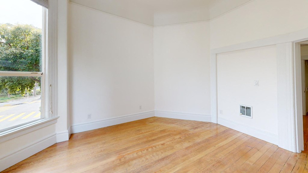 an empty room with white walls and a wood floor