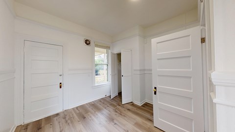 A hallway with white doors and wooden floors.