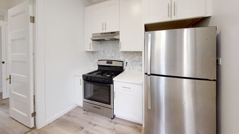 A kitchen with a stainless steel refrigerator and a black stove top oven.