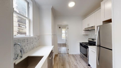 A kitchen with a refrigerator, sink, and oven.