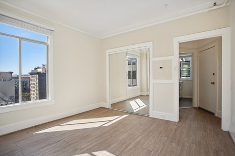 A room with a large window and wooden flooring.