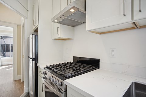 A modern kitchen with a stainless steel refrigerator and a black stove top.