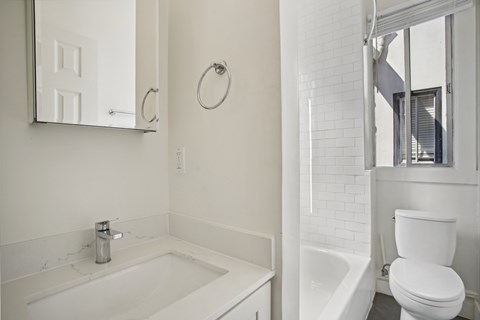 A white bathroom with a tub, toilet and sink.