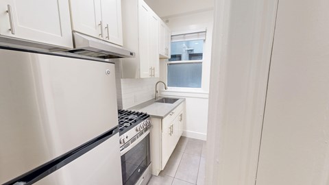 A kitchen with white cabinets and a stainless steel refrigerator.