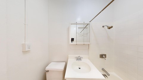 A white bathroom with a toilet, sink, and mirror.