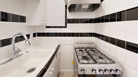 A white and black tiled bathroom with a white sink and a white and black tiled stove.