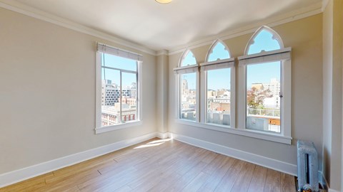 A room with a large window and wooden flooring.