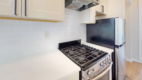A black stove top oven in a kitchen with a white tile backsplash.
