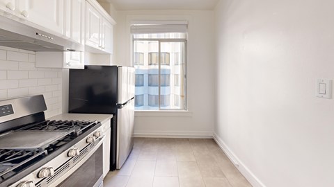 A kitchen with a black fridge and stove top oven.