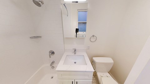 A white bathroom with a sink, toilet and bathtub.