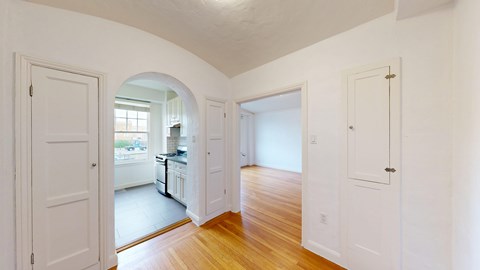 A white interior with a kitchen visible through an archway.