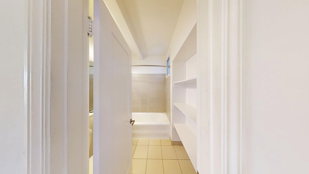 A hallway with white walls and a tiled floor.