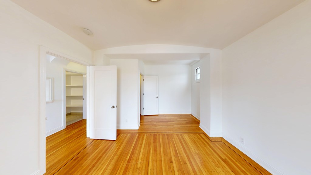 A long hallway with white walls and wood floors.