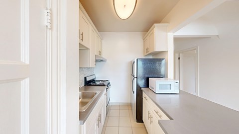 A kitchen with a sink, refrigerator, and microwave.