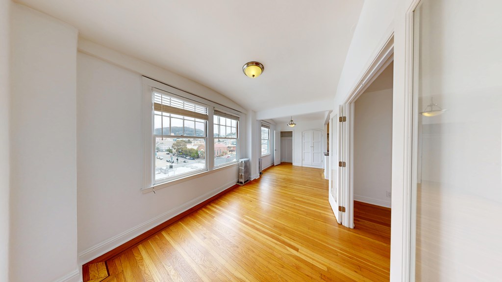 A long hallway with wood floors and white walls.