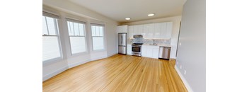 an empty kitchen with wood floors and white cabinets