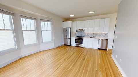 an empty kitchen with wood floors and white cabinets