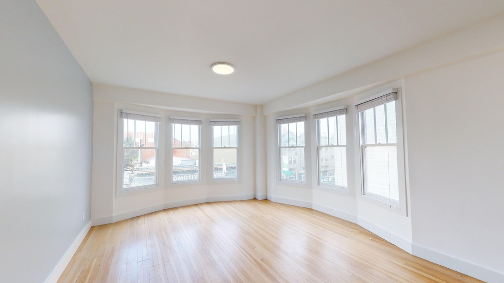 an empty living room with a wood floor and windows