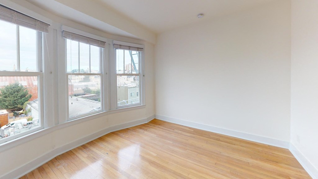 an empty living room with three windows and wood floors